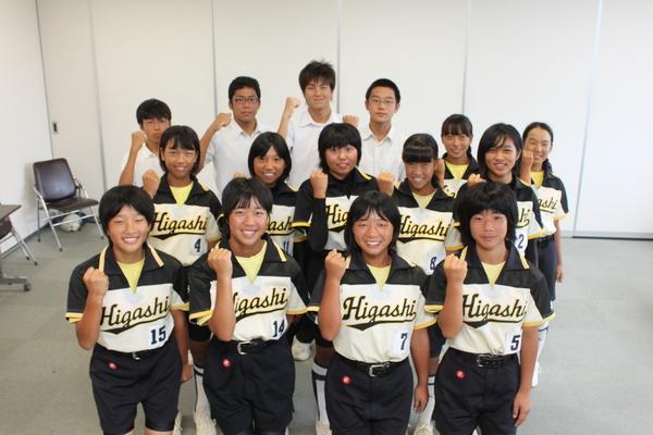 ユニホーム姿の篠山東中学校ソフトボール部女子と制服姿の男子生徒が片手ガッツポーズをしている集合写真